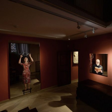 un grande quadro specchiante con una figura femminile che solleva il simbolo del Terzo Paradiso e ritratti di Pistoletto