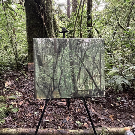 dipinto che ritrae un foresta collocato all'aperto su un cavalletto all'interno della stessa foresta